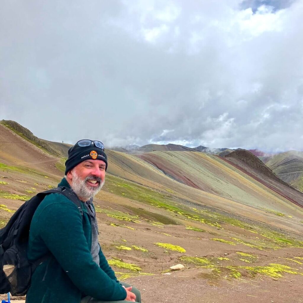 Traveler enjoying the view of Palccoyo Rainbow Mountain colorful stripes in Cusco Peru Andes
