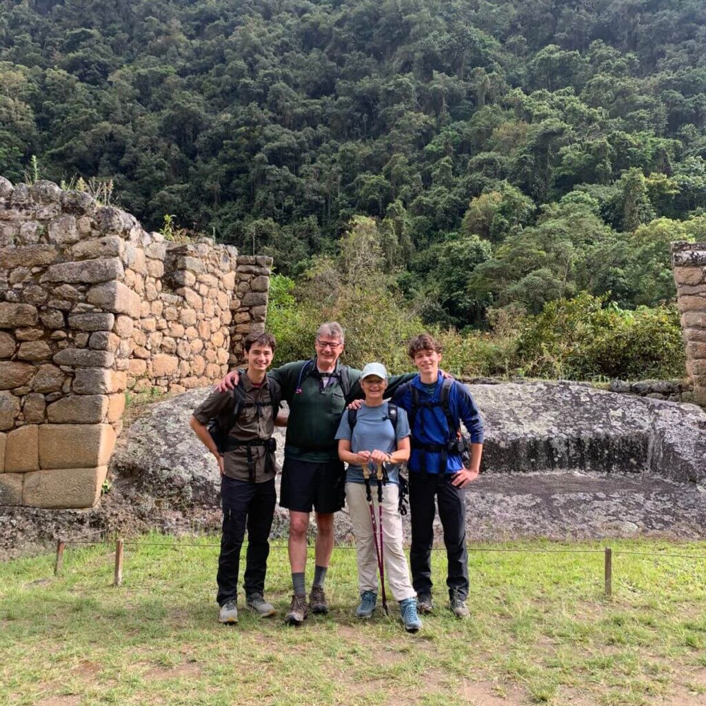 Hikers standing beside Inca stone ruins along the Short Inca Trail, surrounded by lush Andean cloud forest.