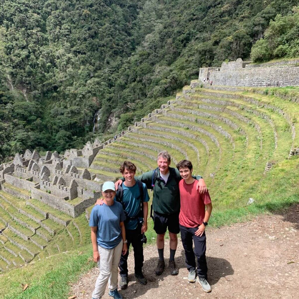 Family of four hikers overlooking the terraces of Wiñay Wayna, an Inca archaeological site along the Short Inca Trail in Peru.