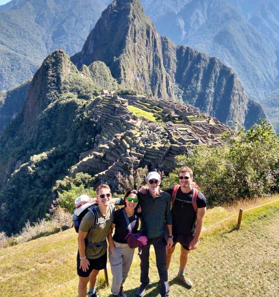 Group of tourists with Machu Picchu citadel and mountains on a sunny day during a Machu Picchu day trip from Cusco.