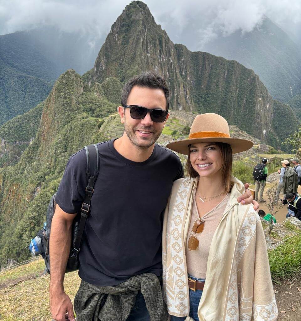 Couple posing at Machu Picchu viewpoint with Huayna Picchu mountain during a Machu Picchu day tour from Cusco.