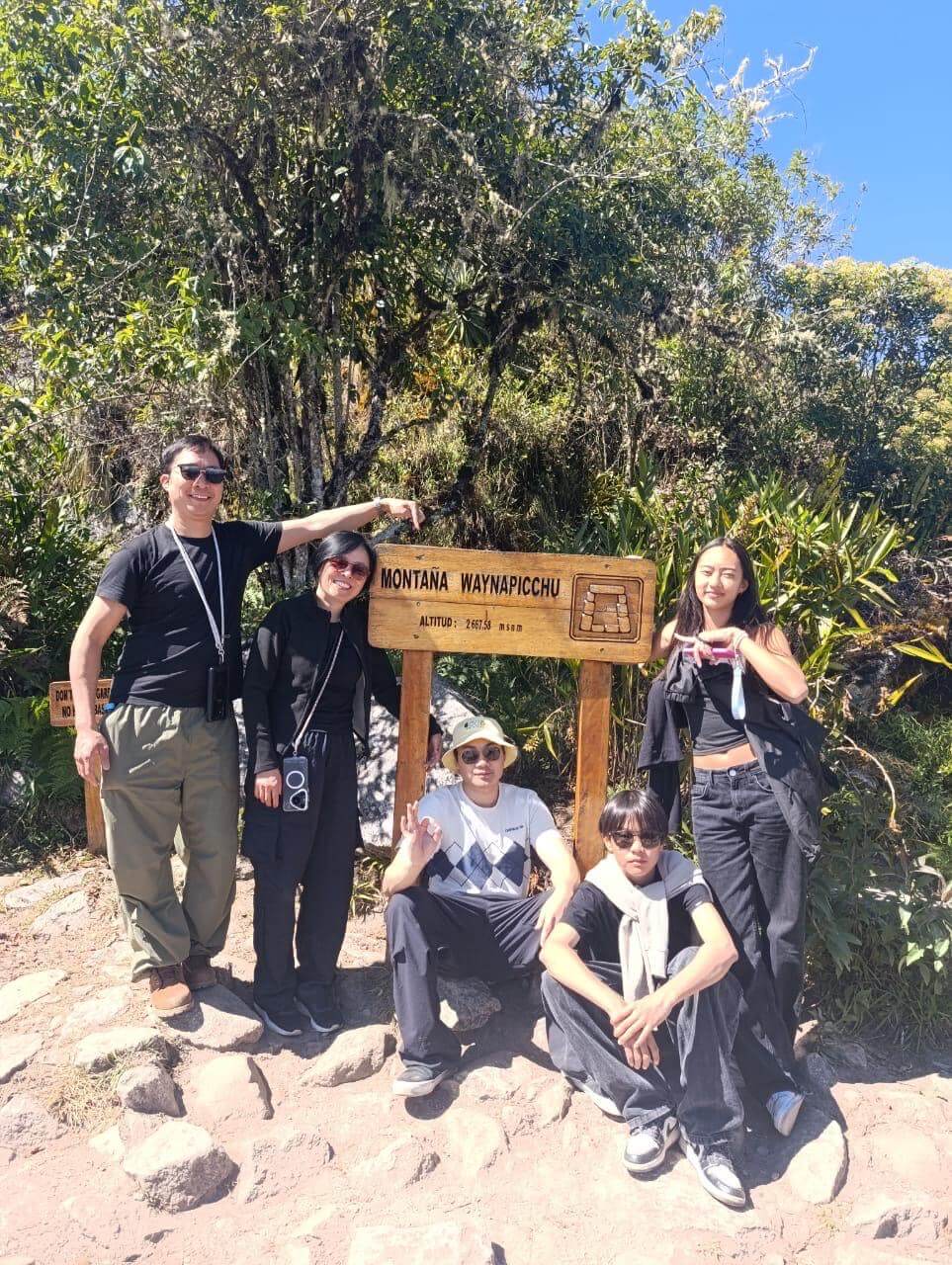 Tourists posing at Waynapicchu mountain sign inside Machu Picchu sanctuary during a Machu Picchu day tour from Cusco.