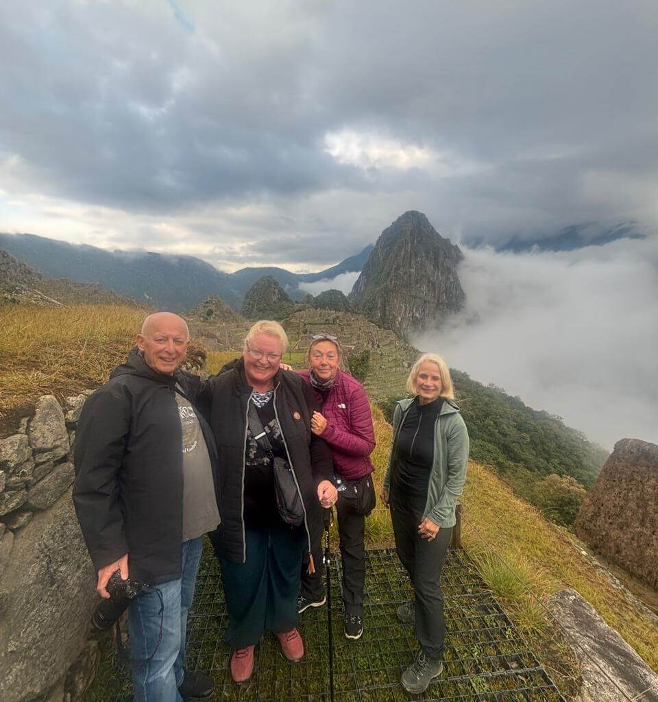 Group standing at high Machu Picchu viewpoint with clouds moving through the Andes mountains.
