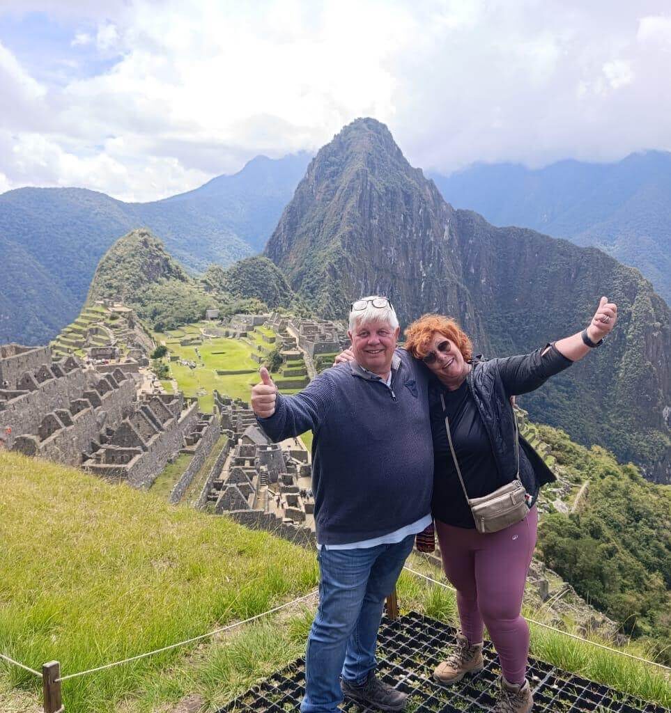 Couple posing and celebrating at Machu Picchu viewpoint with Huayna Picchu mountain behind.